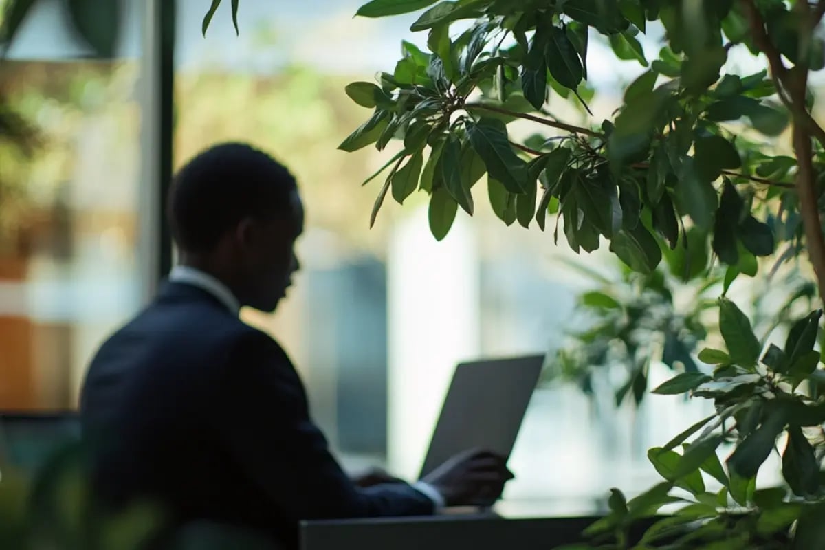 Kenya Drafts Carbon Credit Registry to Boost Global Market Participation_Close-up of a leafy branch with a man working inside a glass office building in Kenya_visual 1